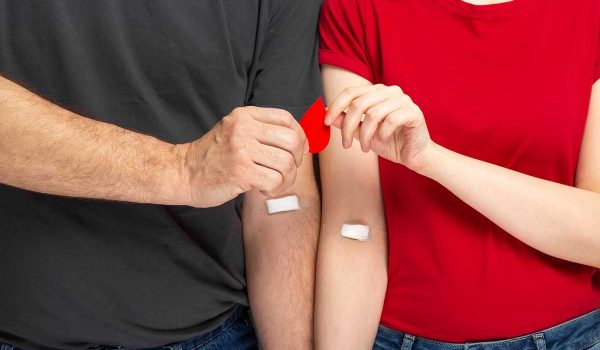 یک زن و شوهر جوان در حال انجام آزمایش خون برای غربالگری قبل از ازدواج. پزشک نمونه خون را از بازوی زن می‌گیرد.
