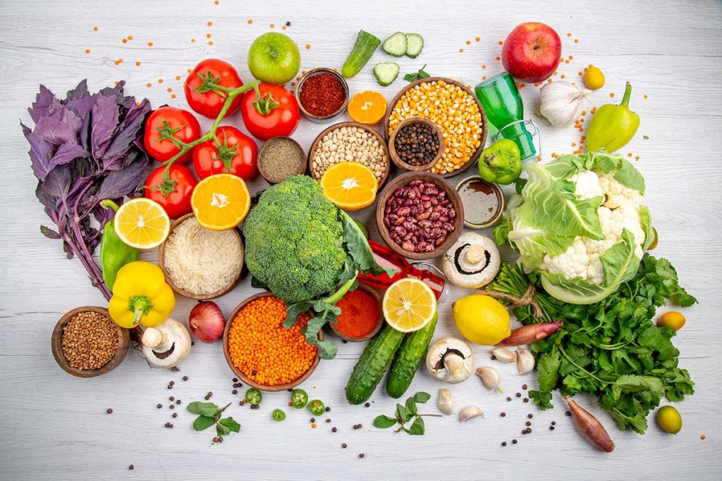 تصویری از مواد غذایی سالم شامل سبزیجات، میوه‌ها، غلات کامل، و منابع پروتئین و چربی‌های سالم که به تقویت سیستم ایمنی بدن کمک می‌کنند
